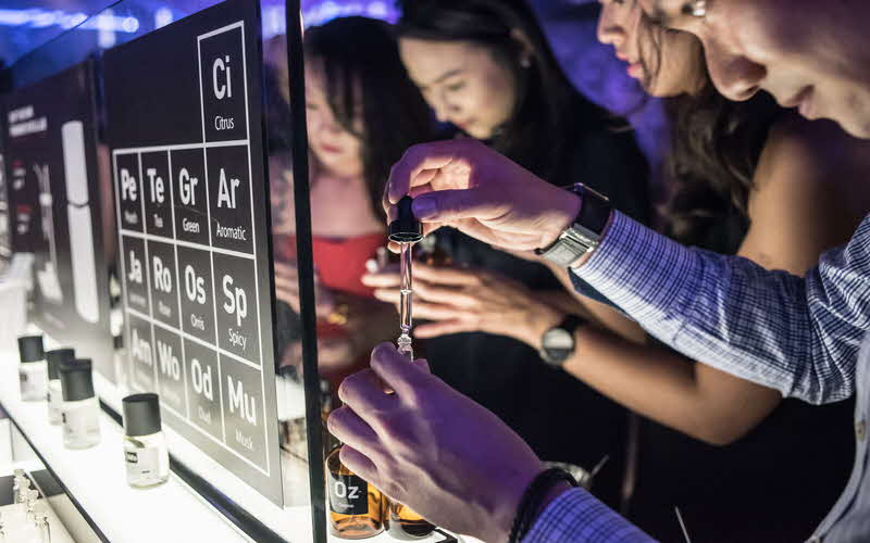 Image of participants creating a custom scent in front of a board which displays different periodic table elements