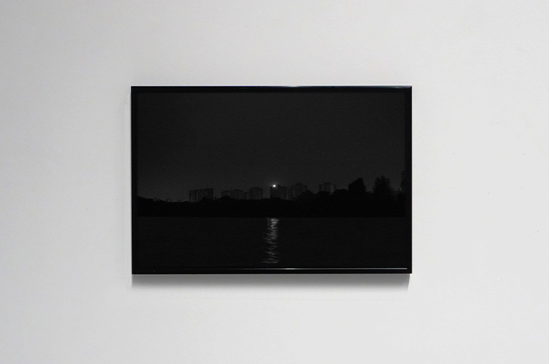Installation shot of a dark photograph on a white wall